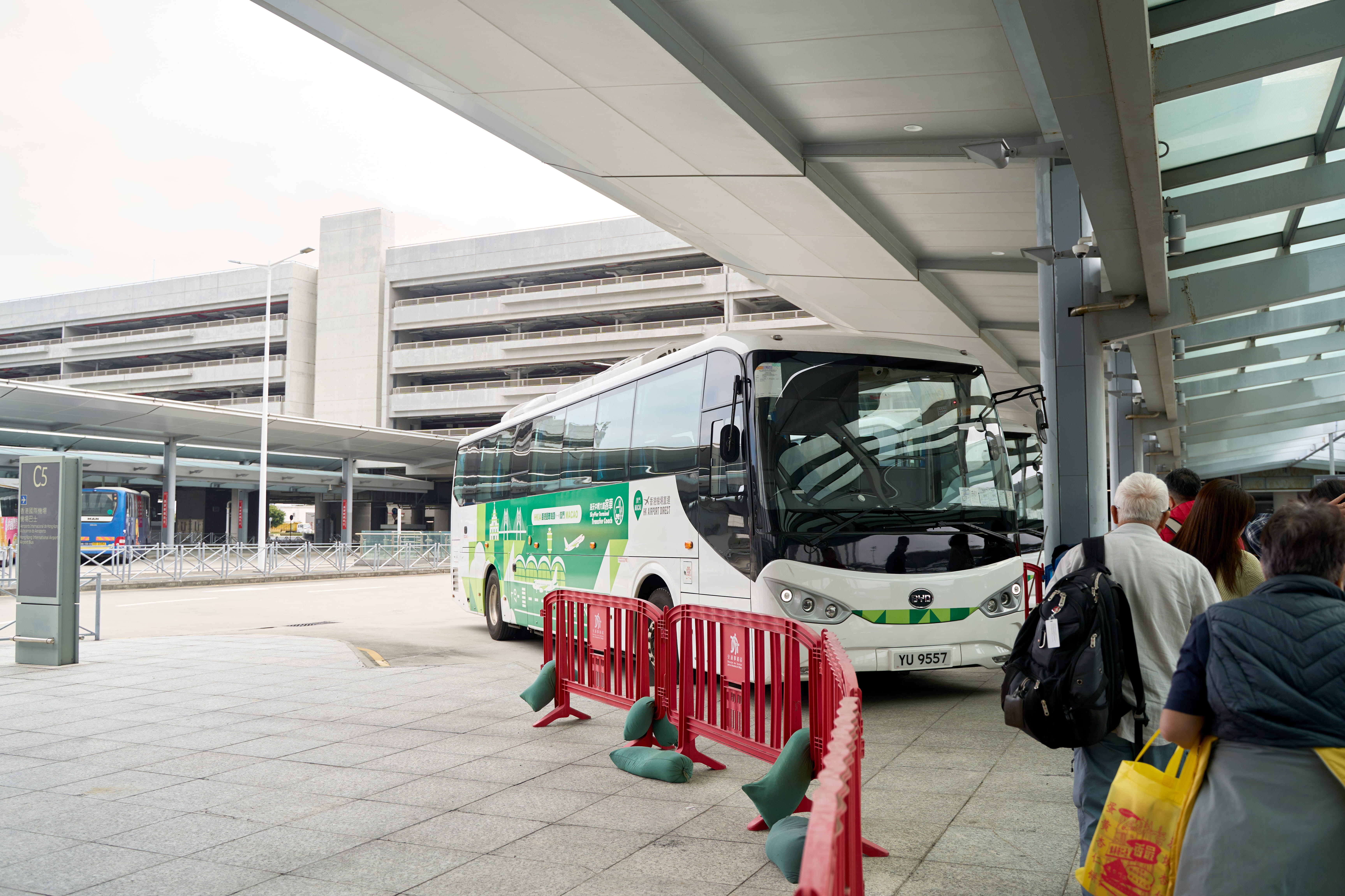 香港国際空港のバス乗り場。乗車を待つ乗客と停車中の白いバス