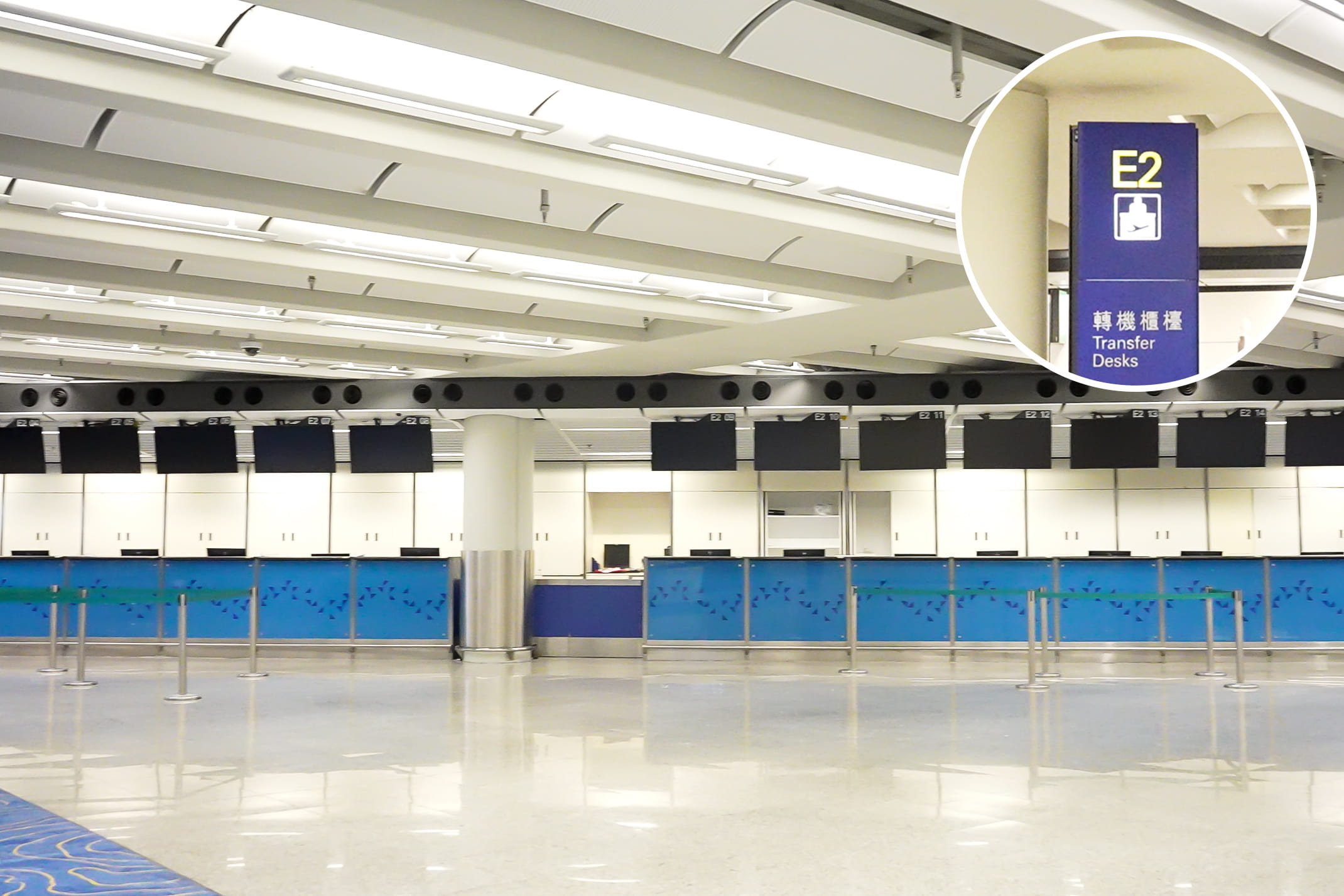 香港国際空港の乗り継ぎカウンター「E2」。青いパネルのカウンターが並ぶ広いロビー