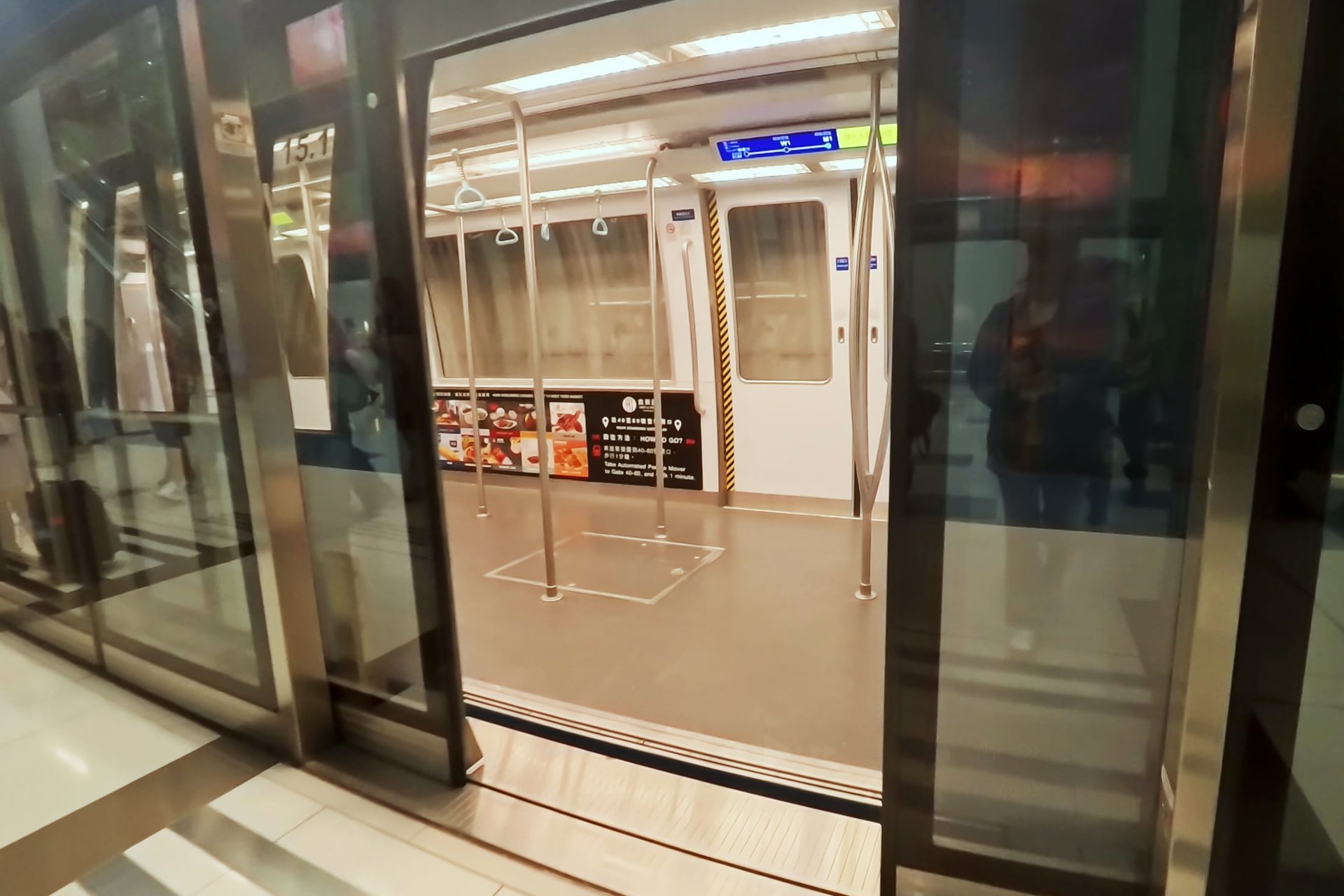 香港国際空港の無人運転シャトル（APM）の車内。ホームドアが開いた状態の無機質な近未来的デザインの車両